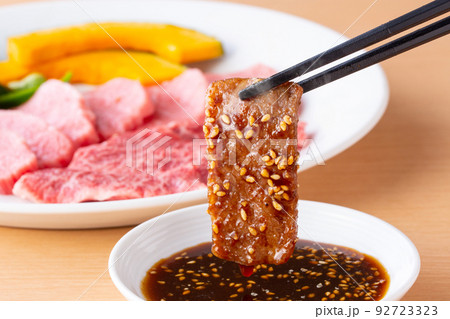 焼肉をタレをつけて食べる 92723323