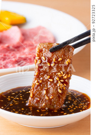 焼肉をタレをつけて食べる 92723325