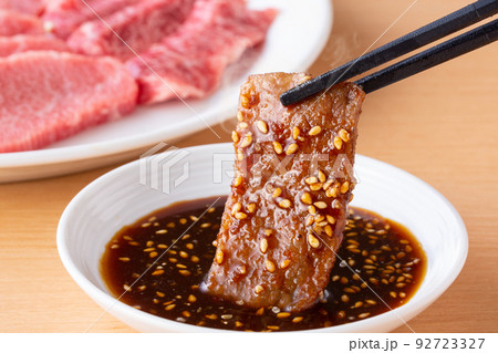 焼肉をタレをつけて食べる 92723327