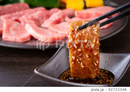 焼肉をタレをつけて食べる 92723346