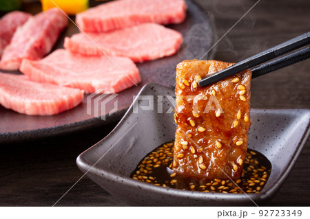 焼肉をタレをつけて食べる 92723349