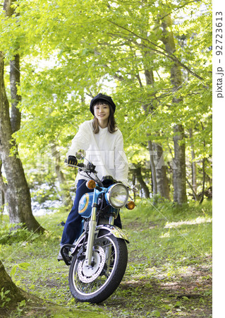バイク女子イメージ　森でバイクに乗ってステップの上に立つ若い女性 92723613