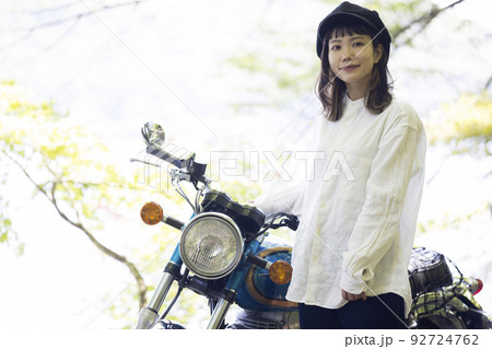 バイク女子イメージ　湖畔でバイクと並ぶ若い女性 92724762