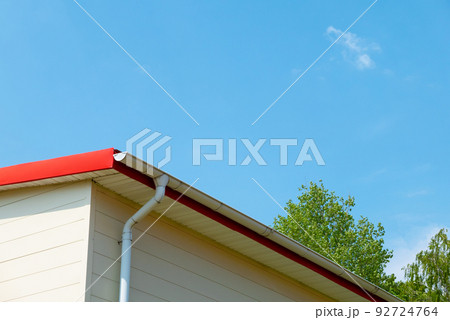 Red gutter on the roof top of house. 92724764