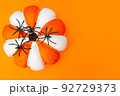 Halloween. White and orange striped pumpkin and black spiders. Place for text. Copy space. Flay lay. Top view. Layout for design. Orange background. Preparation for the Halloween holiday. 92729373