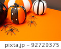 Halloween. Black spiders, four pumpkins in different colors and sizes. Place for text. Copy space. Orange background. Preparation for the Halloween holiday. 92729375