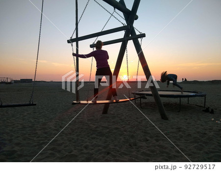 サンセットビーチのサーフボードブランコとトランポリン（スケベニンゲン、オランダ） 92729517