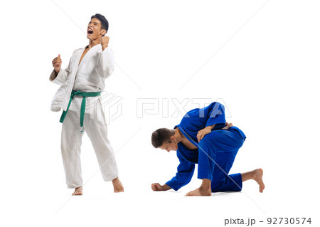 Portrait of two young men, judo athletes showing emotions of win, posing isolated over white background 92730574