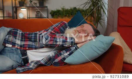 Tired one senior old man lying down in bed taking a rest at home, napping, falling asleep on sofa Tired one senior old man lying down in bed taking a rest at home, napping, falling asleep on sofa 92731089