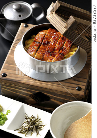 鰻の蒲焼きが入っている釜飯と出汁茶漬けセットを黒背景で撮影 92733537