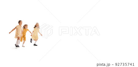 Portrait of three little girls in yellow stylish dresses playing together isolated over white studio background Portrait of three little girls in yellow stylish dresses playing together isolated over white studio background 92735741