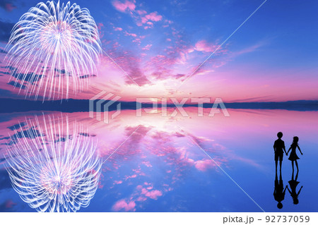 花火と夕焼けを見つめるカップルのシルエット。夏の夕暮れのイメージ。 92737059