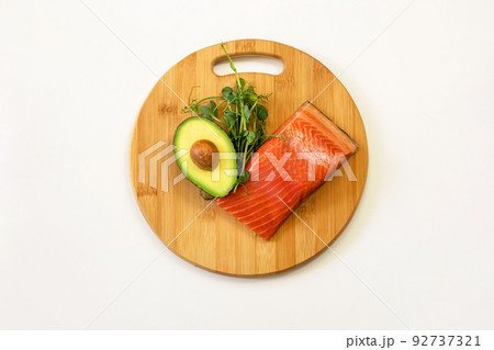 Ingredients of healthy food. Fish, avocado, micro green pea sprouts on a wooden cutting board. Ketogenic low carbs diet concept. Ingredients of healthy food. Fish, avocado, micro green pea sprouts on a wooden cutting board. Ketogenic low carbs diet concept. 92737321
