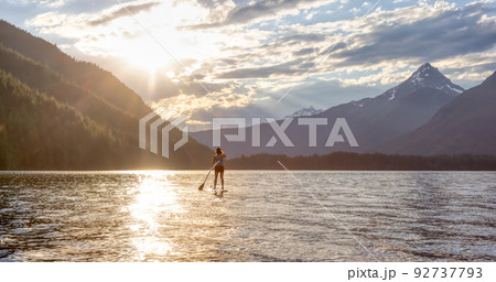 Adventurous Woman Paddle Boarding in a Lake around Canadian Mountain Landscape Adventurous Woman Paddle Boarding in a Lake around Canadian Mountain Landscape 92737793