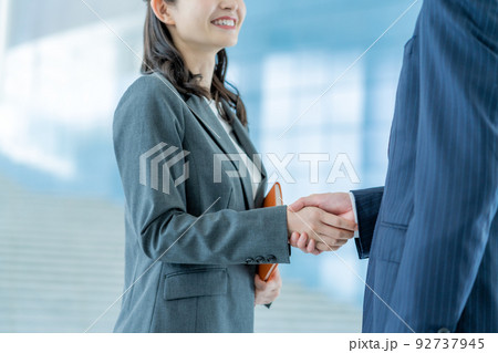 握手するスーツのビジネスマンとビジネスウーマンの手元 92737945