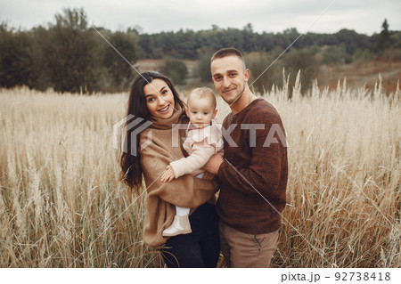 Family with cute little daughter. Father in a brown sweater. Family in a autumn field Family with cute little daughter. Father in a brown sweater. Family in a autumn field 92738418