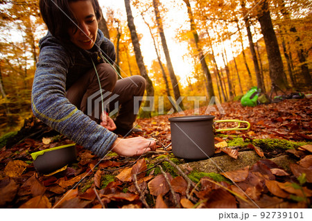 Woman uses portable gas heater and pan for cooking outdoors 92739101