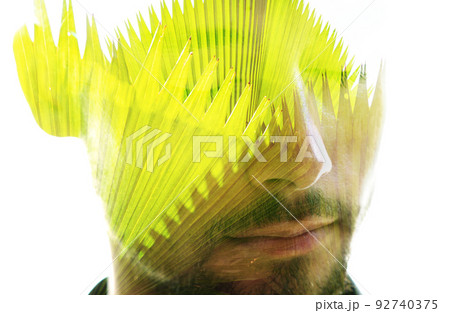 Double exposure portrait of a man combined with an image of a palm leaves 92740375