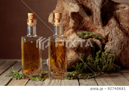 Bottles of olive oil with herbs and spices on an old wooden table. Bottles of olive oil with herbs and spices on an old wooden table. 92740681