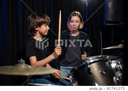 Young woman teaching boy to play drums. Young woman teaching boy to play drums. 92741275