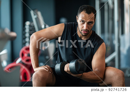 Portrait Of African American Male Athlete Training With Dumbbell At Gym 92741726