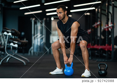 Motivated Young Black Man Training With Kettlebell At Modern Gym Interior 92742088