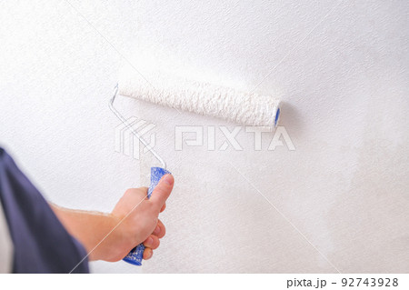 A man is painting vinyl wallpaper with velour A man is painting vinyl wallpaper with velour 92743928