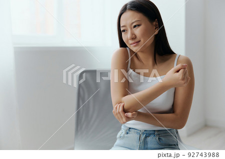 Tormented suffering tanned beautiful young Asian woman hurting holding painful elbow at home interior living room. Injuries Poor health Illness concept. Cool offer Banner Tormented suffering tanned beautiful young Asian woman hurting holding painful elbow at home interior living room. Injuries Poor health Illness concept. Cool offer Banner 92743988