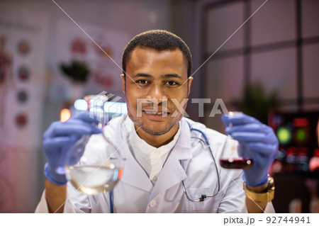 Yong african male scientist working with test tubes wearing lab coat working in laboratory 92744941