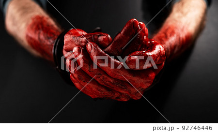 Close-up of male bloody handcuffed hands on a black background. Close-up of male bloody handcuffed hands on a black background. 92746446