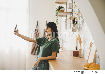 Pretty young asian female with big smile and stand at kitchen room 92748758