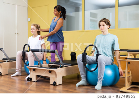 Teenagers under the guidance of pilates trainer are engaged with gymnastic ring on ball Teenagers under the guidance of pilates trainer are engaged with gymnastic ring on ball 92749955