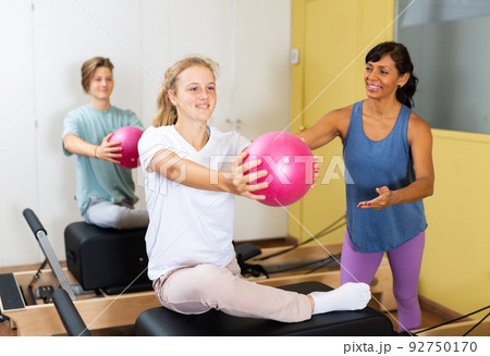 Teens doing pilates exercises with trainer 92750170
