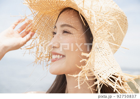ビーチにいる麦わら帽子をかぶったワンピースの女性 92750837