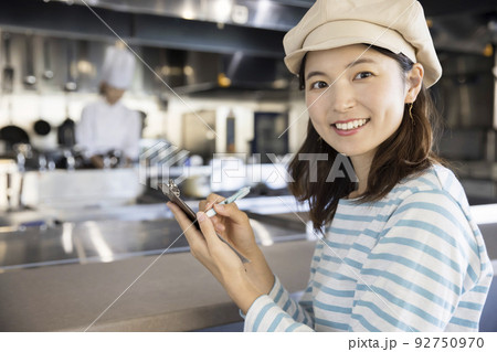 厨房の前に注文伝票を持って立つ若いカフェ店員 92750970