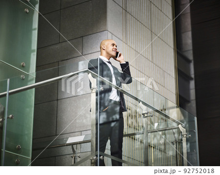 young latino businessman making a call using mobile phone inside modern office building young latino businessman making a call using mobile phone inside modern office building 92752018
