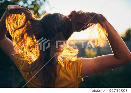 A girl tosses her long beautiful hair in the sun. The concept of hair care and healthy hair. Front view. A girl tosses her long beautiful hair in the sun. The concept of hair care and healthy hair. Front view. 92752303