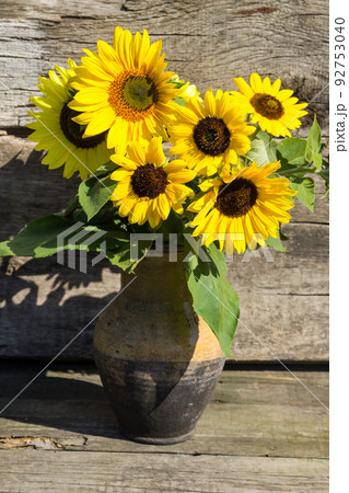 Sunflowers in vintage clay jug on wooden background 92753040