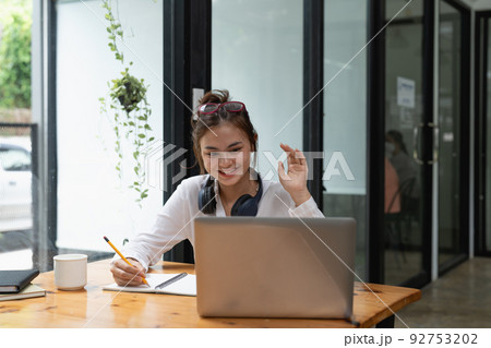 Online education, e-learning. young woman studying remotely, using a laptop, listening and taking note. online webinar at home 92753202