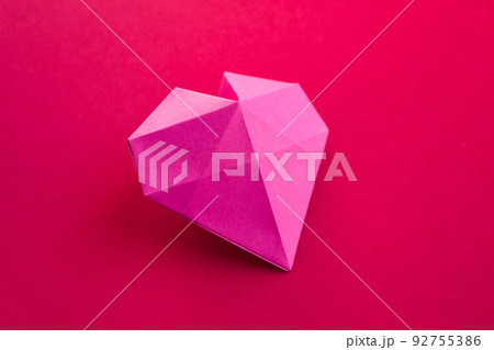 Pink paper heart origami isolated on a red background Pink paper heart origami isolated on a red background 92755386