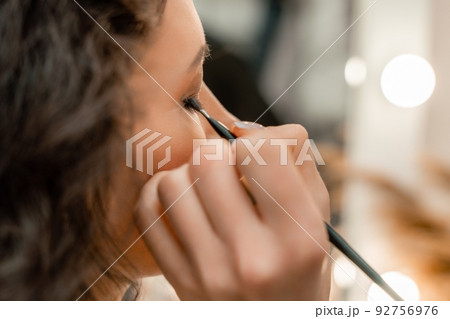 Make-up artist makes a professional make-up of a young woman in the studio. 92756976