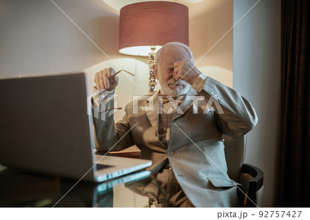 Senior man sitting at the laptop and looking tired Senior man sitting at the laptop and looking tired 92757427