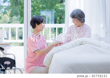 介護 ベットから起きあがるシニアを介助する介護士 介護 ベットから起きあがるシニアを介助する介護士 92758132