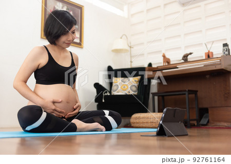 Asian pregnant woman practicing yoga online 92761164