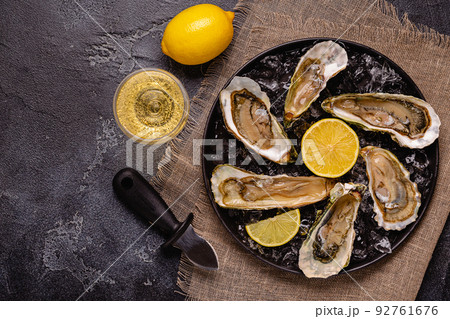 Opened fresh oysters on a plate, served with lemon and ice. Opened fresh oysters on a plate, served with lemon and ice. 92761676