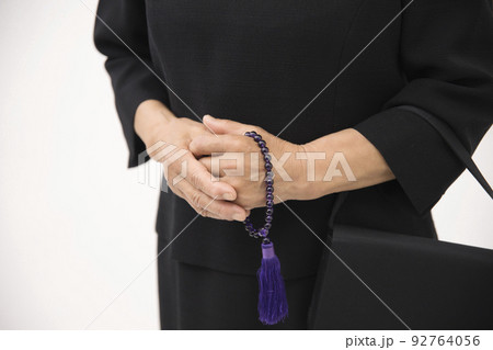 喪服を着たシニア女性の数珠を持つ手元 92764056
