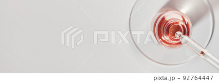 Oil or Serum bottle and pipette in petri dish on grey banner. Pink cosmetic product 92764447