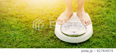 Woman standing on the white scales with bare feet in nature. 92764974