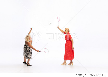 Two charming senior women in retro vintage dresses posing isolated on white background. Concept of beauty, old generation, fashion, emotions Two charming senior women in retro vintage dresses posing isolated on white background. Concept of beauty, old generation, fashion, emotions 92765610
