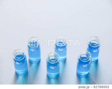 白い画用紙の上に並べた青色の液体が入った6個のガラス瓶 白い画用紙の上に並べた青色の液体が入った6個のガラス瓶 92766002